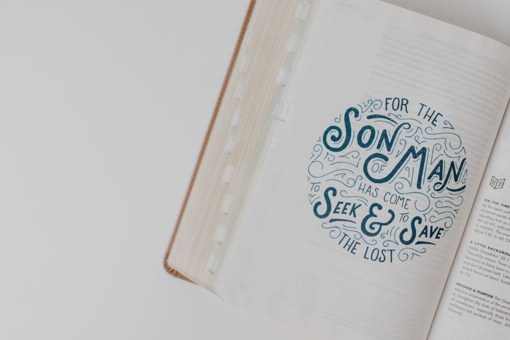 High-angle view of an open Bible with an inspirational scripture quote on a white surface.
